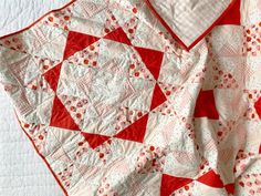 a red and white quilt is laying on the bed with it's edge down