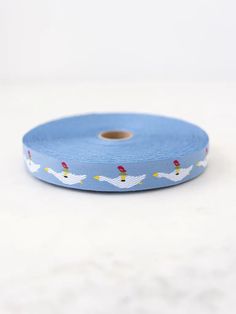 a roll of blue ribbon with white birds on the front and yellow dots on the back