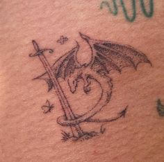 a dragon tattoo on the back of a woman's shoulder and chest, with an arrow in the middle