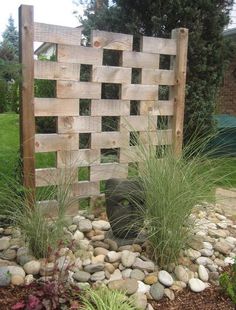 a wooden fence surrounded by rocks and plants in a garden with grass growing around it