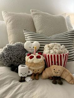 stuffed animals are sitting on the bed with popcorn and cakes in front of them,