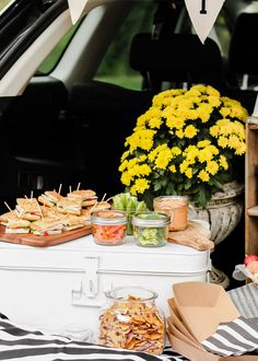 an open trunk filled with food next to flowers