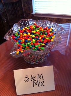 a glass bowl filled with lots of candy on top of a table next to a sign