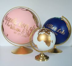 three colorful globes with names on them are sitting on a table next to each other