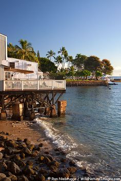 a house sitting on top of a pier next to the ocean