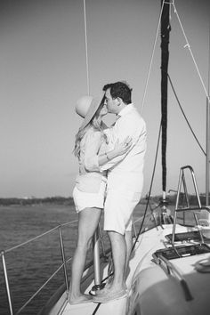 a man and woman kissing on the deck of a sailboat at sea in black and white