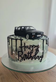 a birthday cake with a car on top and the words happy birthday written in black