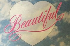 the word beautiful written in pink on a white heart - shaped sticker against a blue sky with clouds