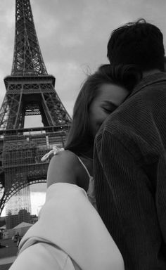 a man and woman kissing in front of the eiffel tower