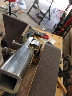 a machine that is sitting on top of a piece of wood in a room filled with tools