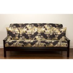 a black and white couch sitting on top of a hard wood floor next to a wall