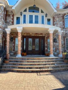 a large house with steps leading up to the front door and entry way that has pumpkins on it