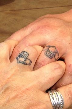 two people holding hands with tattoos on their fingers