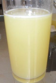 a glass filled with yellow liquid sitting on top of a counter