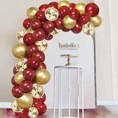 a red and gold balloon arch is shown in front of a white stand with balloons on it