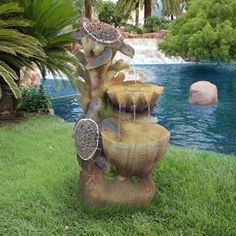 a water fountain in the middle of a lawn next to a pool and palm trees