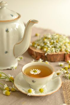 a tea cup and saucer sitting on a table with flowers in the foreground