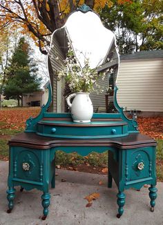 a blue vanity with a mirror and vase on it in front of a house outside