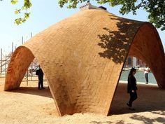 people are walking around in the sand near a structure that is shaped like an umbrella