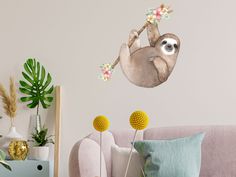 a wall decal with a sloth hanging from a branch and flowers on it