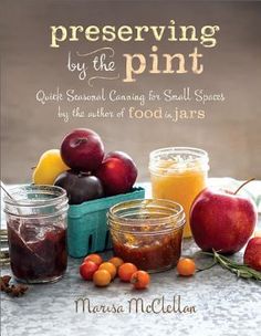 a book on preservers sitting on top of a marble counter with apples and oranges