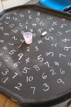 a chalkboard with numbers written on it and a plastic cup sitting on the table