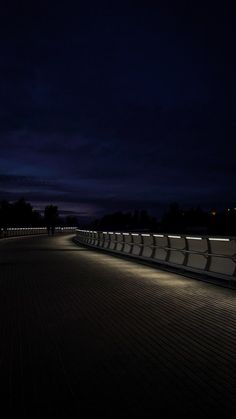 a bench sitting on top of a wooden floor under a dark sky with clouds in the background