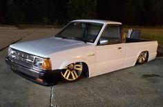 a white pick up truck with gold rims parked in a parking lot at night