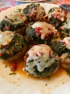 several stuffed mushrooms covered in cheese and sauce on a plate with a fork next to it