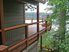 there is a wooden deck on the side of this house that overlooks a lake