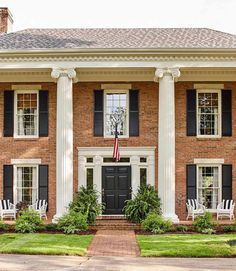 a large brick house with columns and black shutters