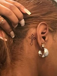 a close up of a person with a cross tattoo on their back of the ear