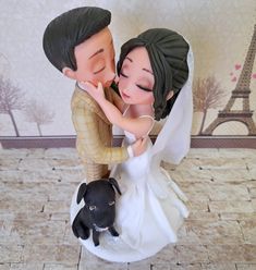 a figurine of a bride and groom kissing next to a dog on a tile floor