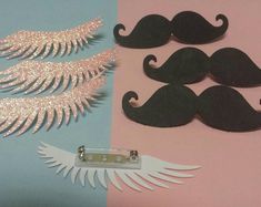 some paper cut outs are next to a pair of fake moustaches on a pink and blue background