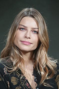 a woman with long blonde hair and blue eyes is looking at the camera while wearing a black shirt