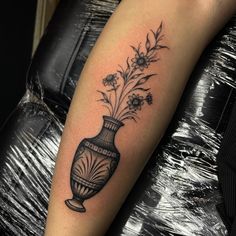 a black and white photo of a vase with flowers on it's arm,