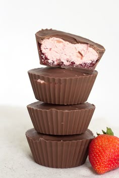 three chocolate cups stacked on top of each other next to a strawberry