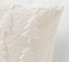 a white pillow with snowflakes on it and a christmas tree embroidered on the back