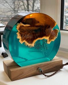 a blue glass plate sitting on top of a wooden stand in front of a window