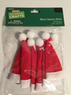 three red and white santa hats with pom - poms on the top are packaged in plastic