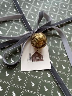 a gift wrapped in gray ribbon with a house ornament on it