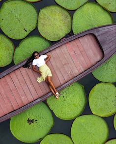 a woman laying on top of a boat surrounded by lily pads