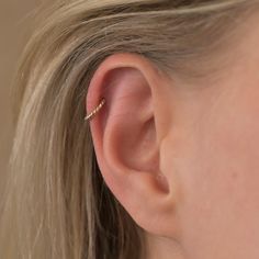 a close up of a person wearing a gold ear cuff