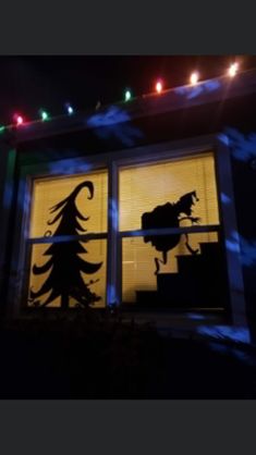 the silhouette of a horse is seen through an open window at night with christmas lights in the background