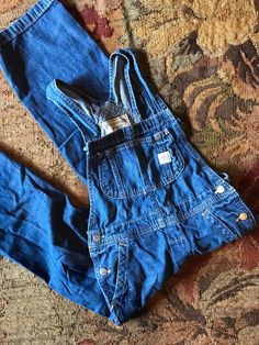 Vintage Ralph Lauren Overalls Sweet little miniature version of the classic workwear staple Workwear style denim with tons of style and pockets Comfy, soft, distressed wash denim  Great, flexible closet staple Buttons on hips to get on and off easily Adjustable 2 buttons for straps Polo Ralph Lauren Listing is for the overalls only; not display pieces or other apparel or decor Size Childs size 7 Approximate measurements in inches (lying flat): -waist: 12-13 -hip:14 -length:43 -inseam:21 Utility Denim Overalls For Everyday, Everyday Denim Jumpsuit With Pockets, Everyday Denim Overalls With Pockets, Everyday Medium Wash Denim Overalls, Distressed Dark Wash Cotton Overalls, Distressed Cotton Overalls In Dark Wash, Dark Wash Distressed Cotton Overalls, Casual Distressed Denim Overalls, Everyday Dark Wash Denim Overalls