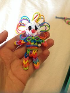 a hand holding a small colorful toy in it's left hand next to a crochet hook