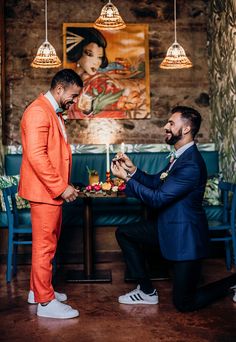 two men in suits standing next to each other near a table with candles on it