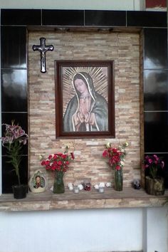 flowers and candles are placed on the mantle in front of a painting depicting the virgin mary