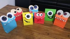 some paper bags that have eyes and mouths on them, sitting on a wooden table