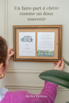 a woman holding up a framed photo in front of a sign that says, un faire - part d'cher comment un doux souvenir